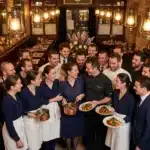 Équipe de restaurant joyeuse posant avec plats cuisinés